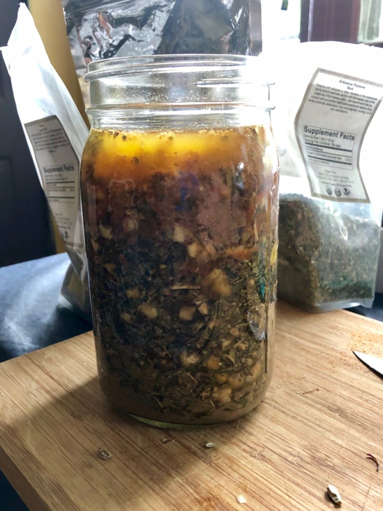 a jar of herbs covered in apple cider vinegar and alcohol